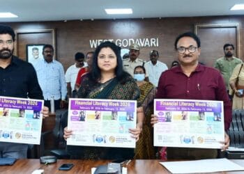 District Collector Chadalavada Nagarani unveiling the Financial Literacy Week 2026 awareness wall poster at the District Collectorate conference hall with officials present.